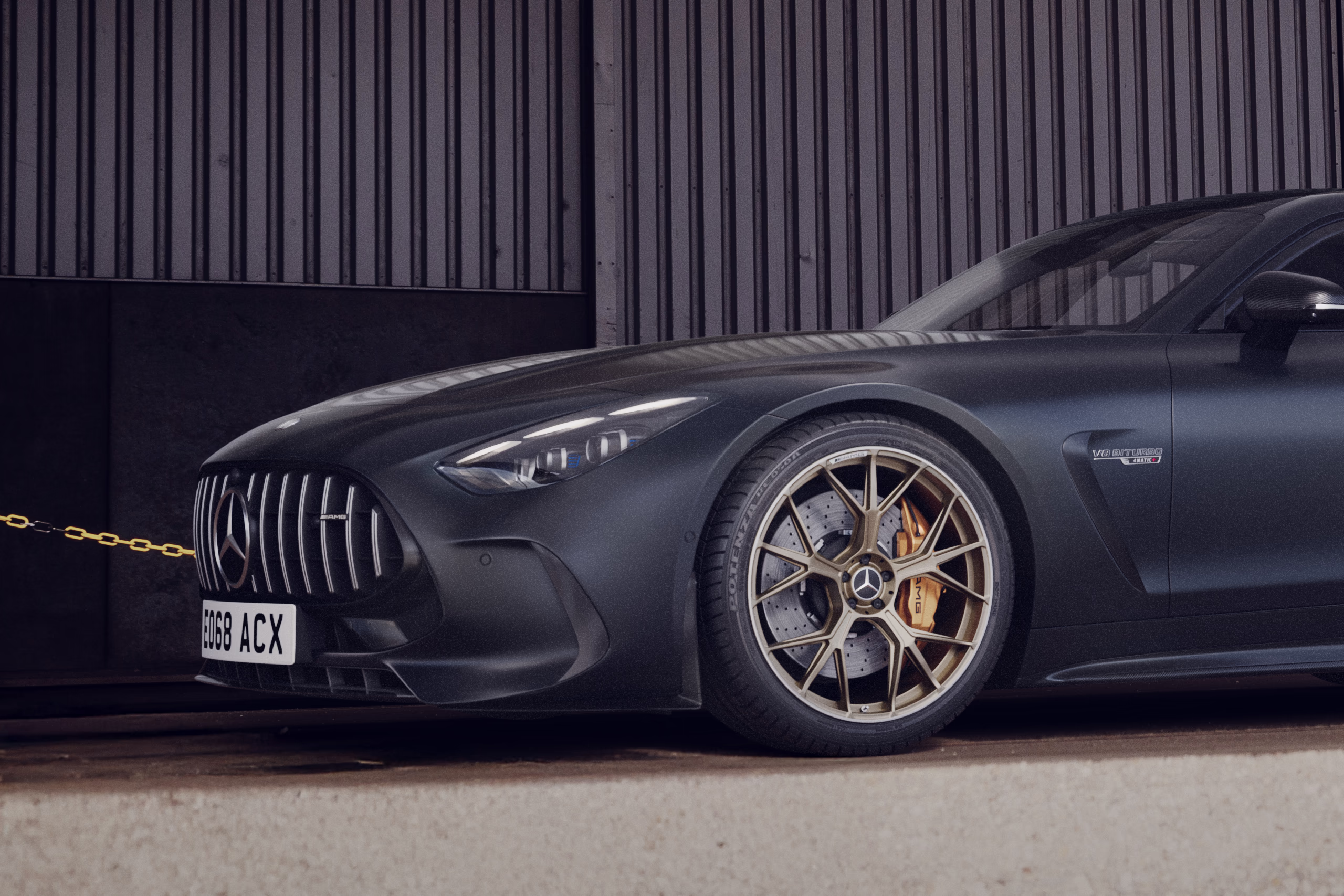 Mercedes AMG GT CGI visual showing a close-up of the front wheel, grille and headlight in a dark industrial setting.